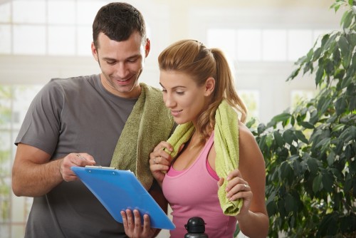 man and woman in gym looking at exercise plan