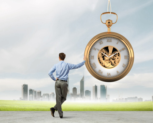 man standing confidently beside large watch