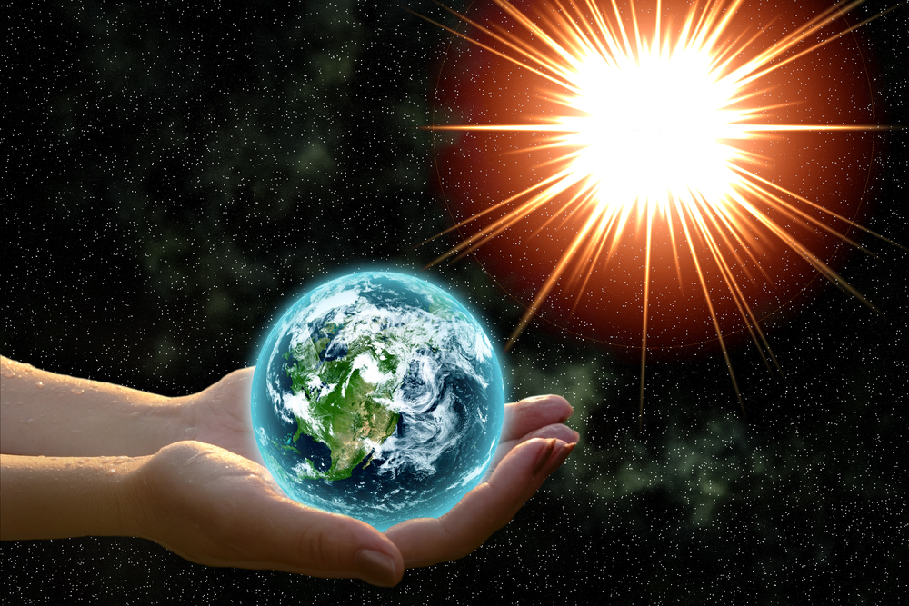 hands holding planet Earth in sunlight