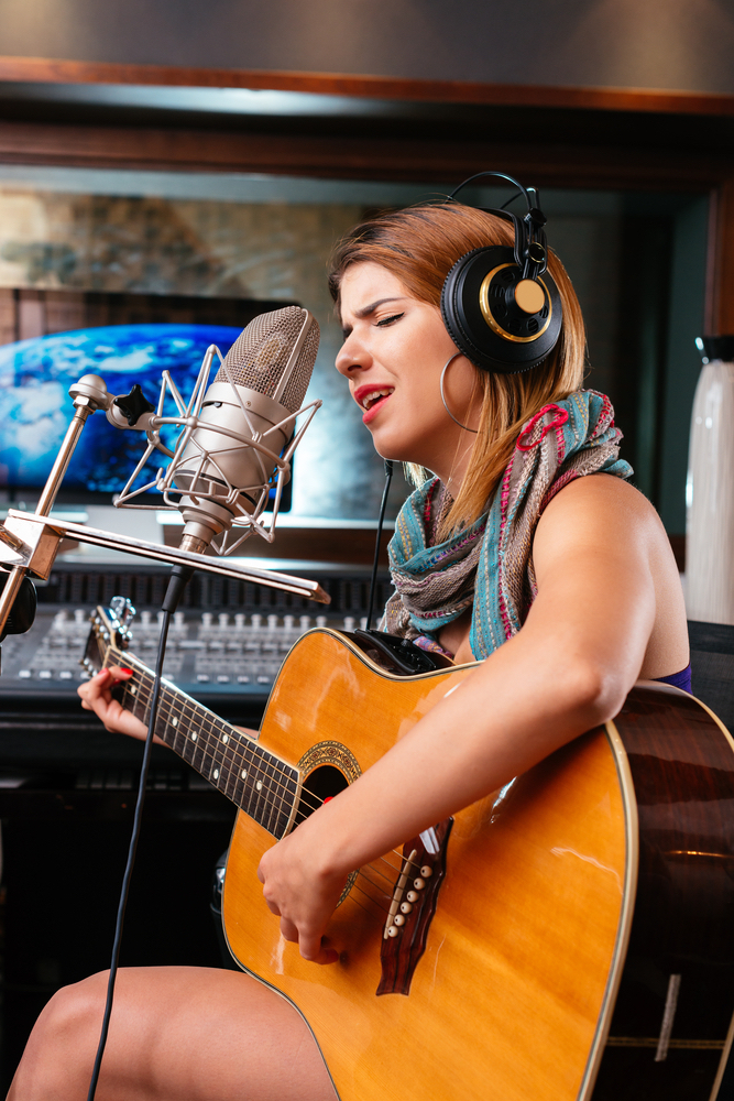 woman playing guitar in recording studio