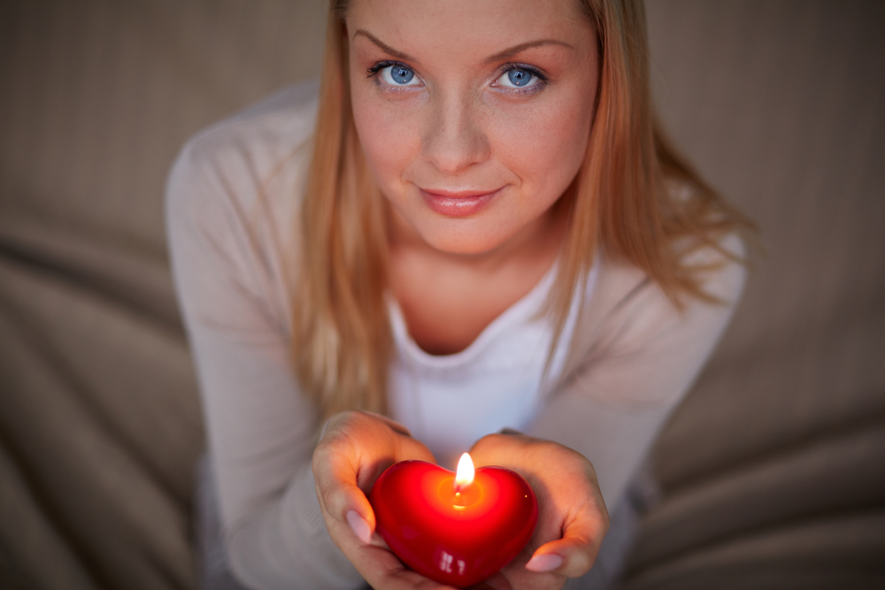 woman holding heart-shaped candle in her hands