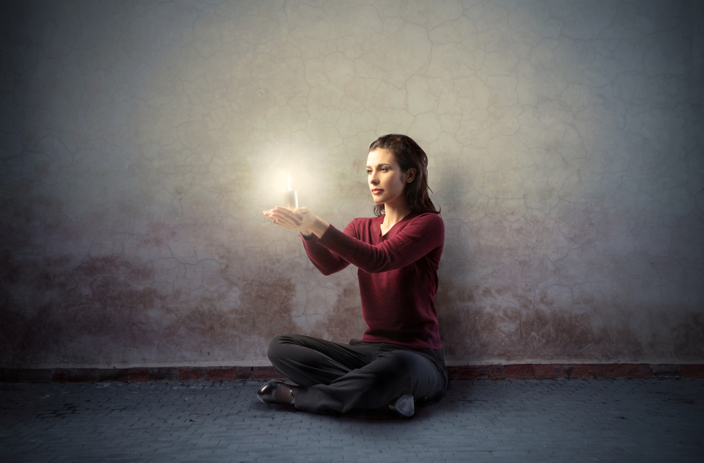 woman seated and holding white candle