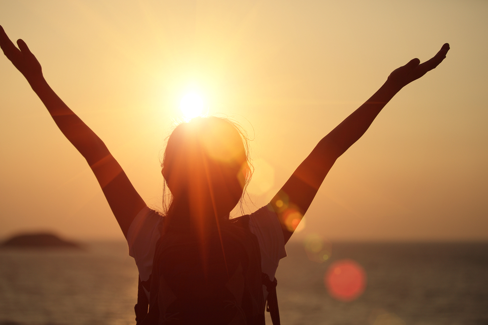 woman with arms extended in sunlight