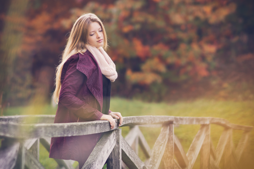 Woman standing on bridge looking pensive. Ego, judgement compared to self-love, self-worth