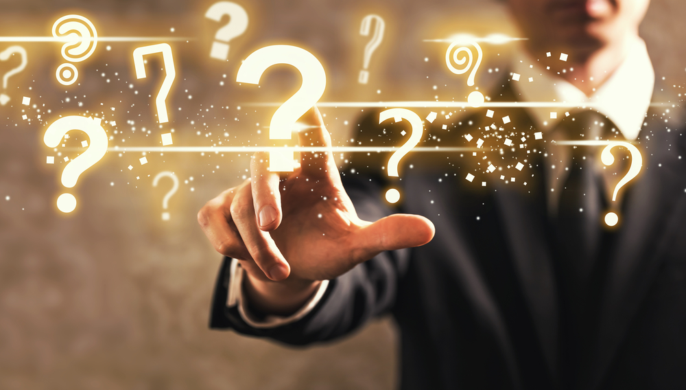Man reaching out towards question marks hovering before him