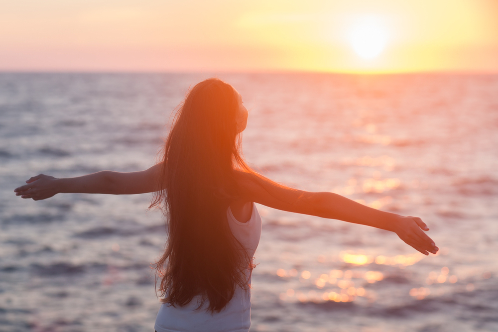 Happy woman looking at sunset over ocean