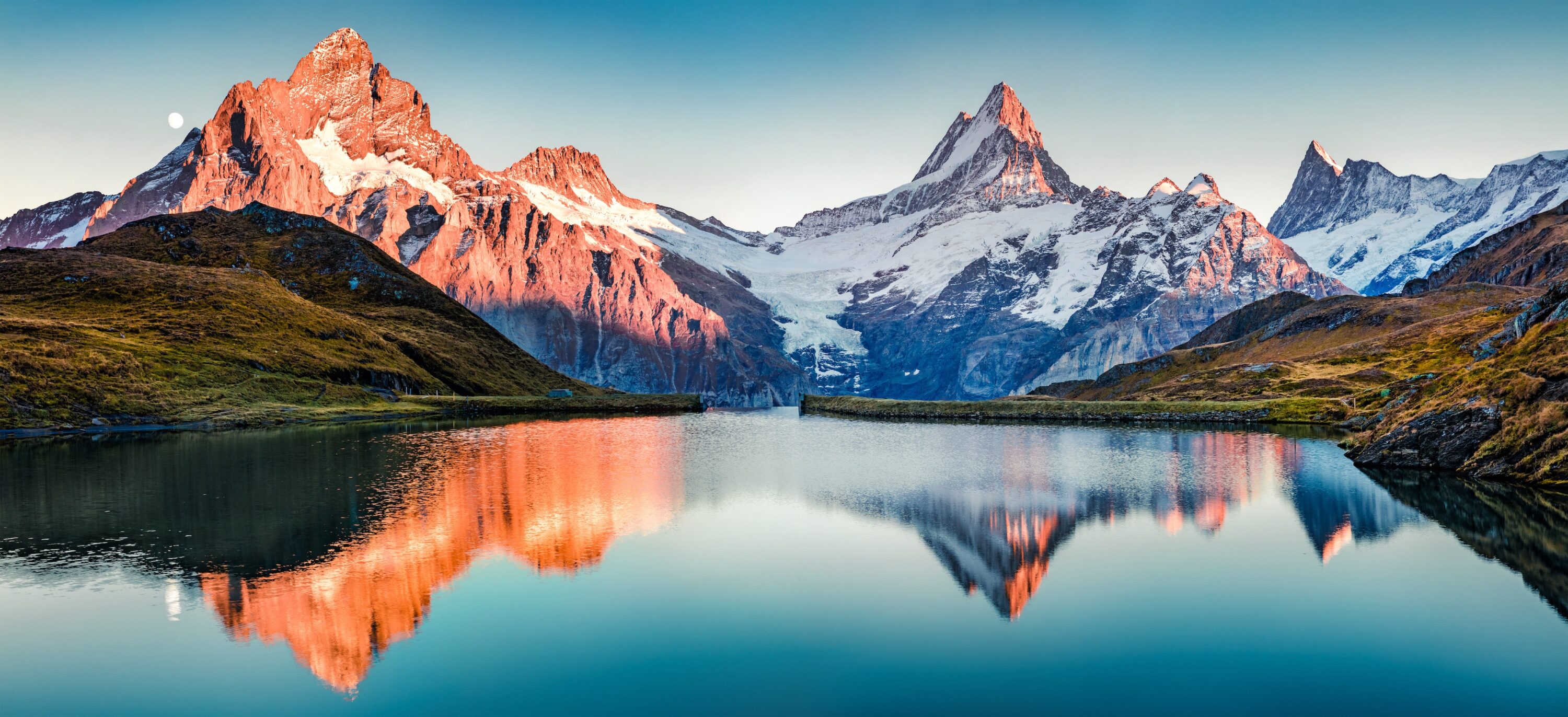 Mountains at dawn mirrored perfectly in a still alpine lake